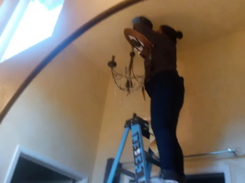 Electrician installing a chandelier in a Kronenwetter residence